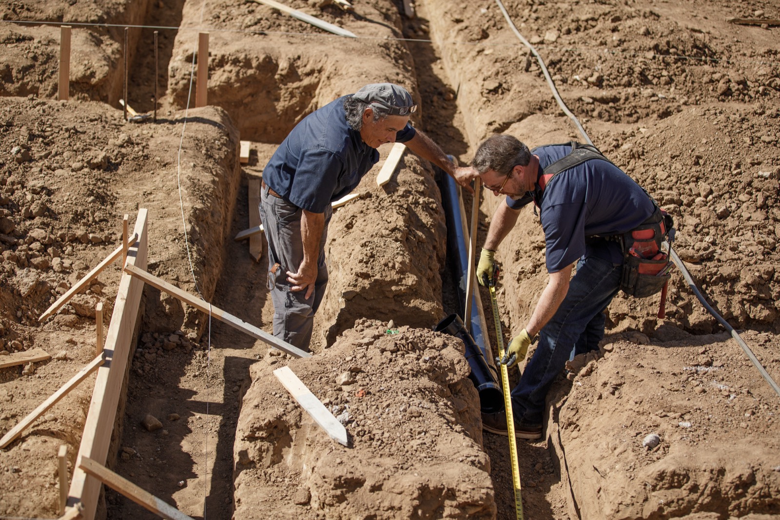 Pipe Perfection crew setting underground drain line in a new-construction trench